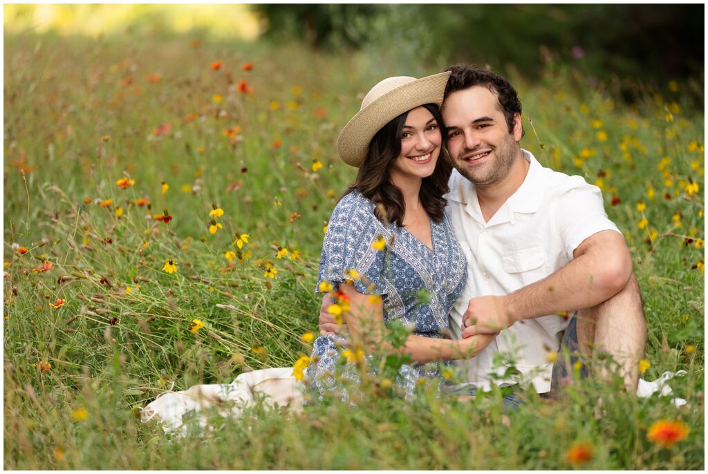 A couple sitting in the wild flowers at Kathryn Albertson Park in the summer.